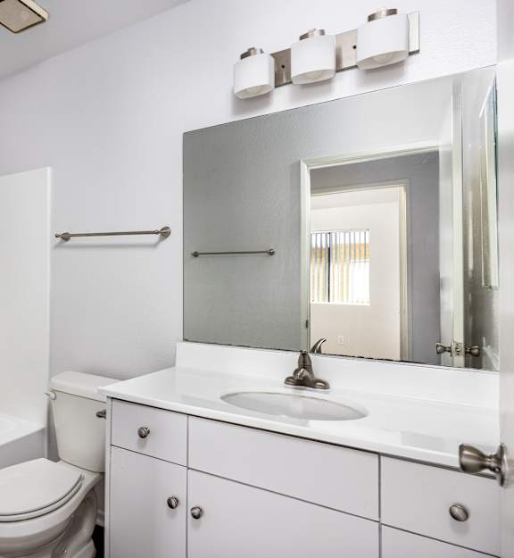 A white bathroom with a toilet, sink, and mirror.