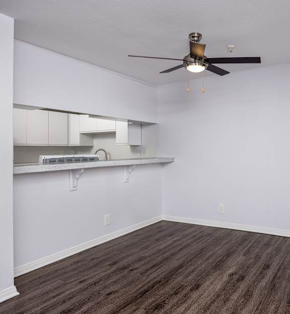 A room with a ceiling fan and wooden flooring.