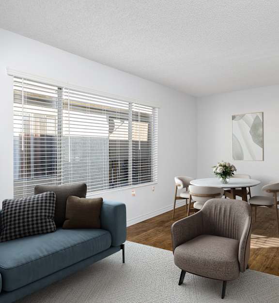 A living room with a blue couch, a grey armchair, a white table, and a television.