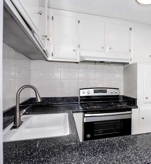 A kitchen with a black granite countertop and white cabinets.