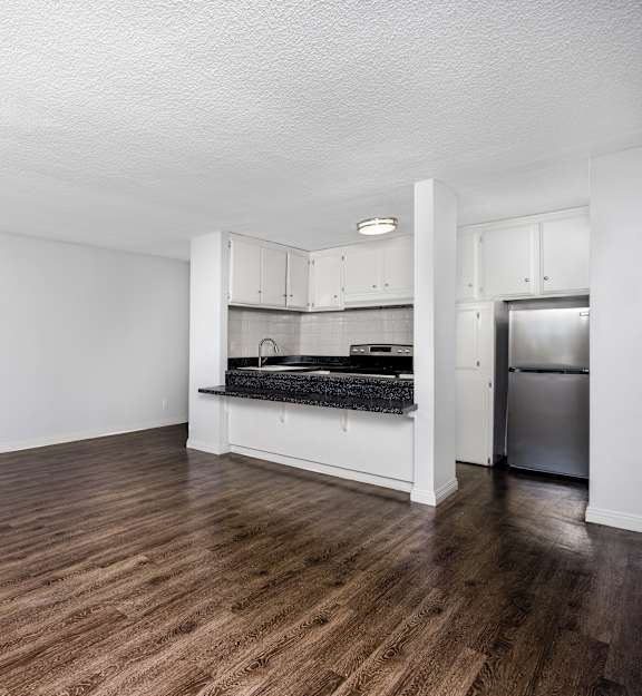 A kitchen with a stainless steel refrigerator and wooden floors.