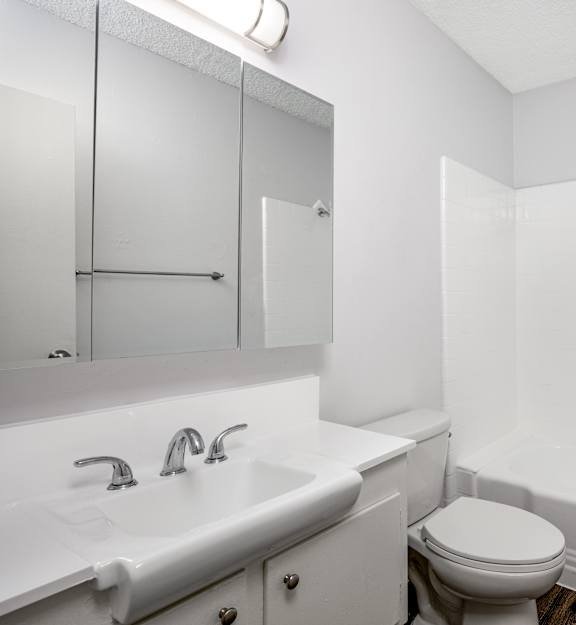 A white bathroom with a toilet, sink, and bathtub.