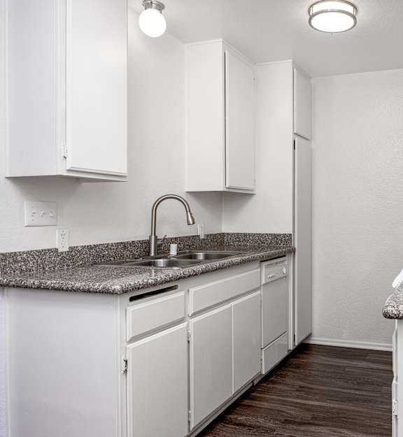 A kitchen with white cabinets and a granite countertop.