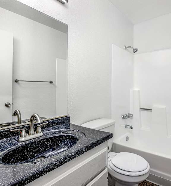 A bathroom with a black granite countertop and white fixtures.