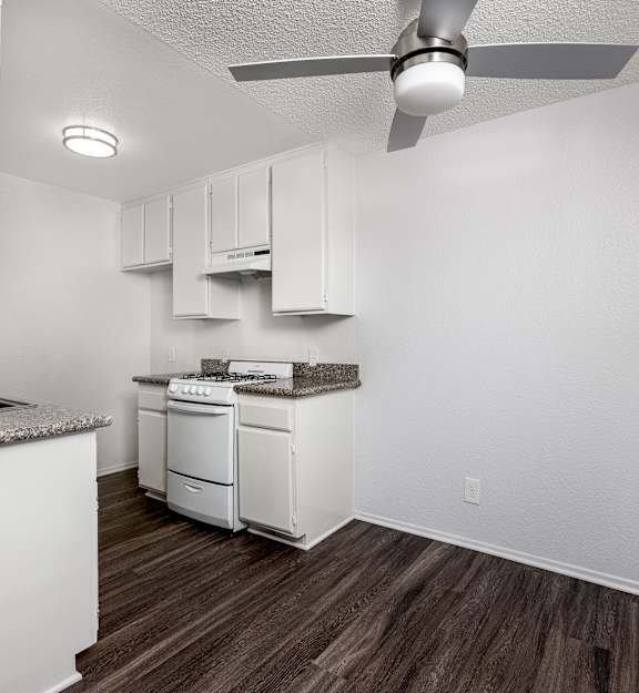 A kitchen with white cabinets and a wood floor.