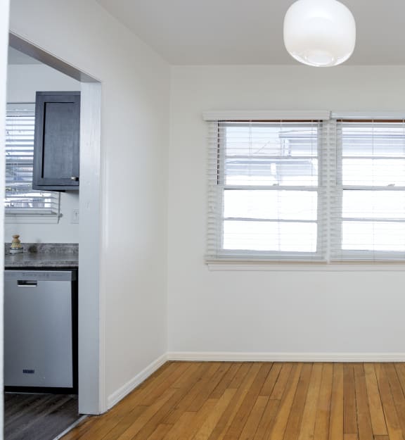 an empty living room with a window and a kitchen