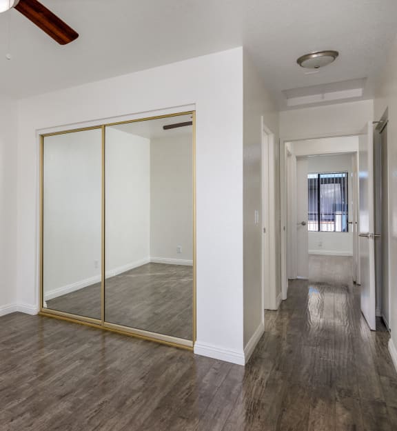 an empty room with a ceiling fan and a mirrored closet