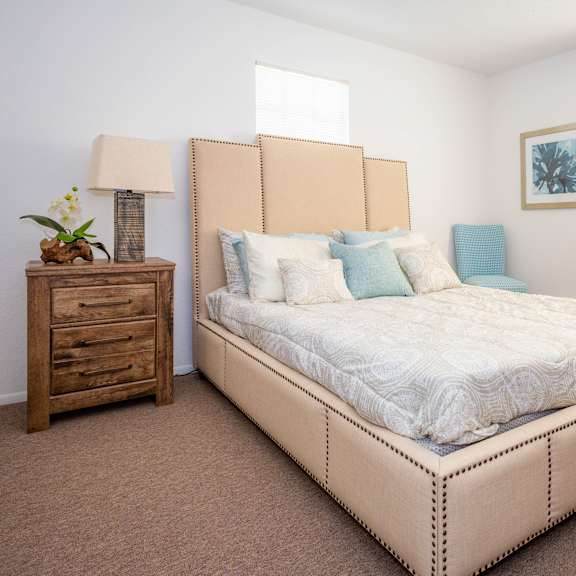 A bedroom with a large bed, a wooden nightstand, and a window.