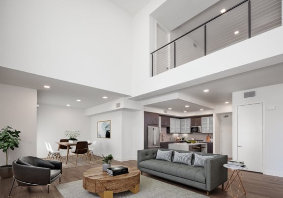 a living room with a couch and a coffee table in front of a kitchen with a breakfast