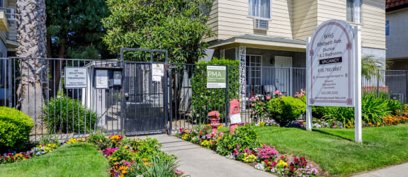 a home with a sign and flowers in front of it