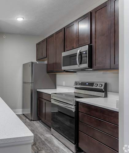 A kitchen with a white countertop and dark brown cabinets.