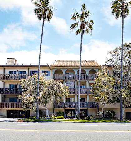 an apartment building with palm trees in front of it