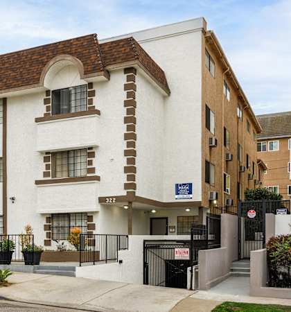 A white and brown building with a black gate in front.