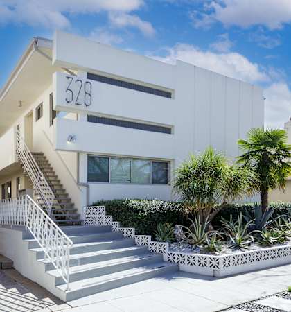 a white building with a staircase and palm trees in front of it