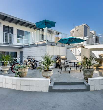 A patio with a table, chairs, and plants.
