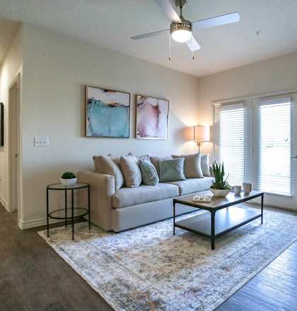 a living room with white walls and a ceiling fan
