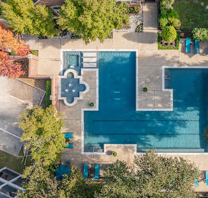 An aerial view of a swimming pool surrounded by trees and a small building.