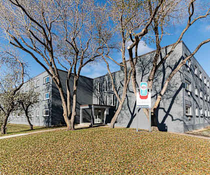 A grey building with a sign in front of it.