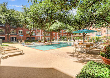A pool surrounded by trees and chairs.
