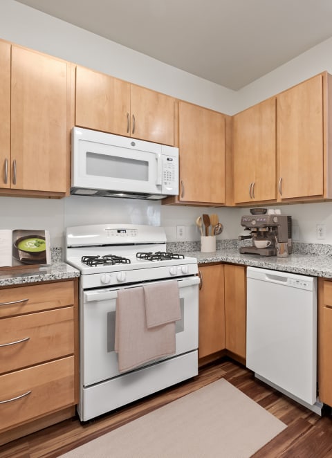 a kitchen with wooden cabinets and white appliances and granite counter tops at Sandy Creek Apartments, Bryan, TX