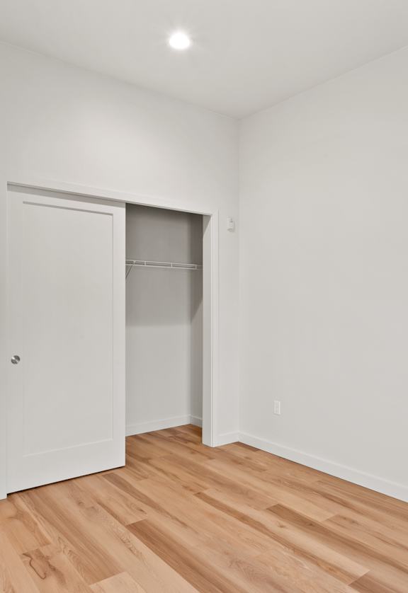 A room with white walls and wooden flooring with three white doors.