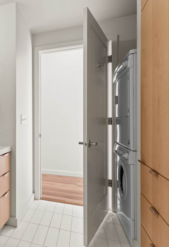 A bathroom with a sink, mirror, and a washer and dryer in the doorway.
