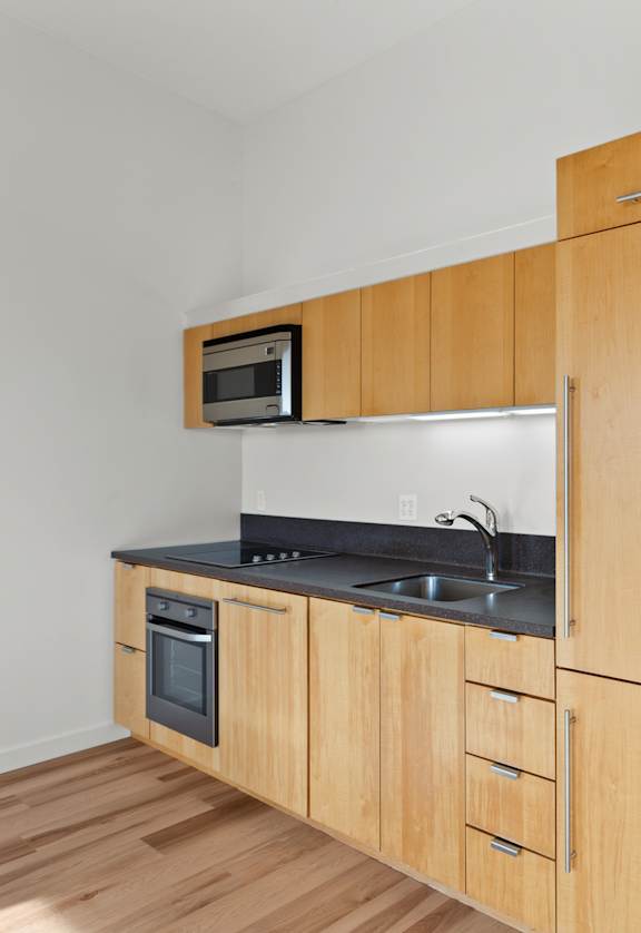 A kitchen with wooden cabinets and a microwave above the stove.