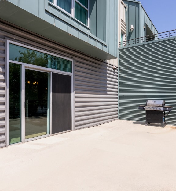 a patio with a grill and a building with glass doors