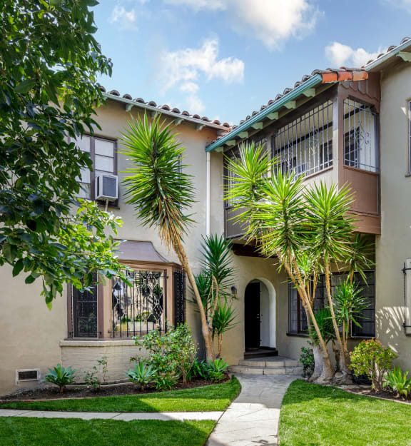 a house with a yard and palm trees in front of it