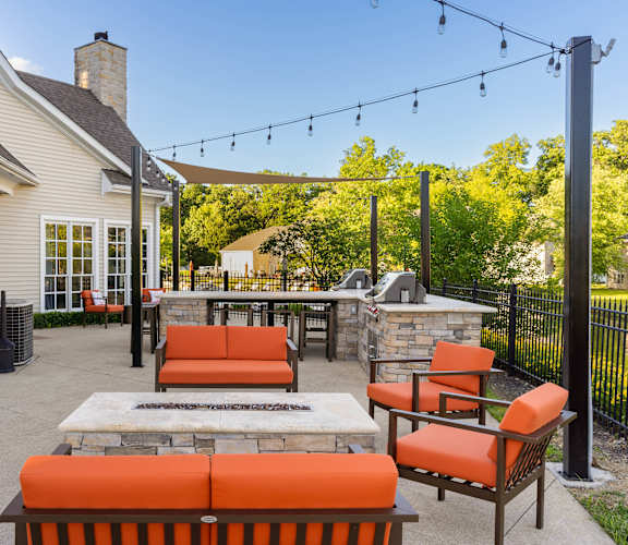 a patio with orange furniture and a stone fireplace
