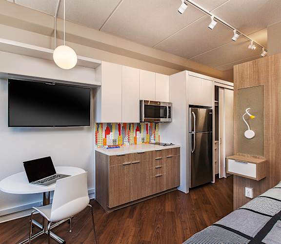 A modern kitchen with a refrigerator, microwave, and a television mounted on the wall at 28Grand, Detroit, MI