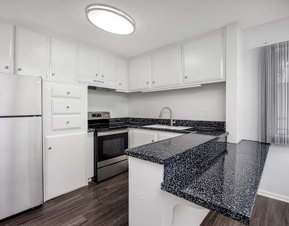 A kitchen with white cabinets and a black granite counter.