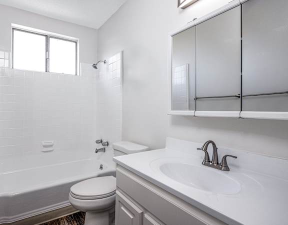 A white bathroom with a toilet, sink, and bathtub.