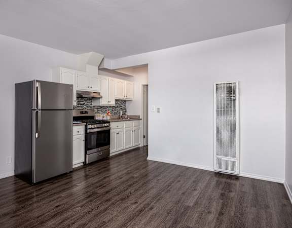 A kitchen with a refrigerator, oven, and cabinets.