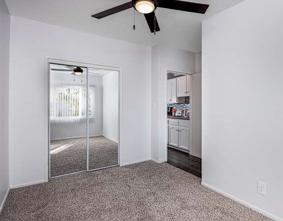 A room with a ceiling fan and a sliding glass door leading to a balcony.