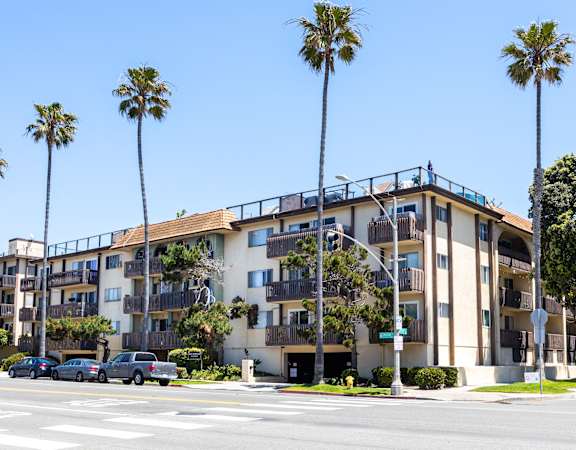 an apartment building on a street with palm trees