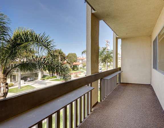 a balcony with a view of the street and palm trees