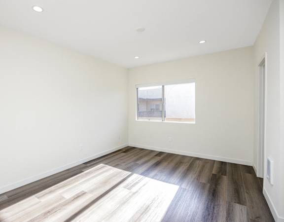 an empty room with wood floors and a window