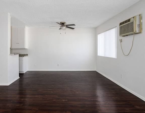 an empty living room with wood floors and a ceiling fan