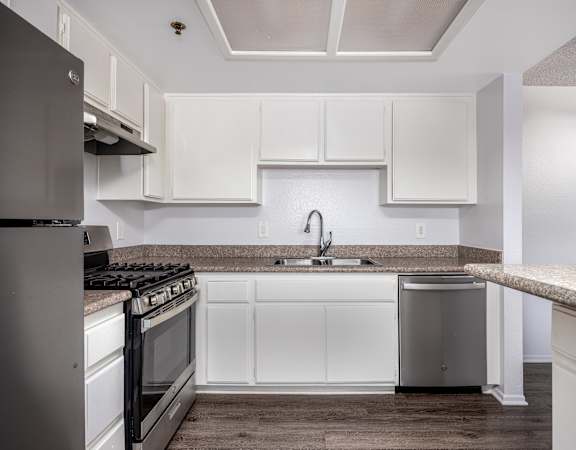 A kitchen with white cabinets and a granite countertop.