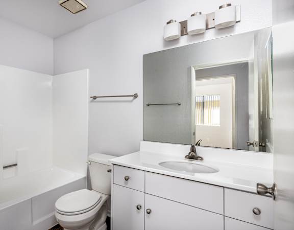 A white bathroom with a toilet, sink, and mirror.