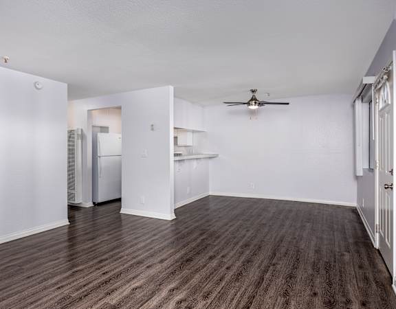 A room with a ceiling fan and wooden flooring.