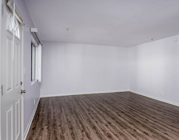 A room with wooden flooring and white walls.