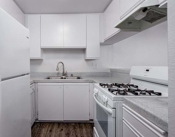 A white kitchen with a refrigerator, stove, and cabinets.