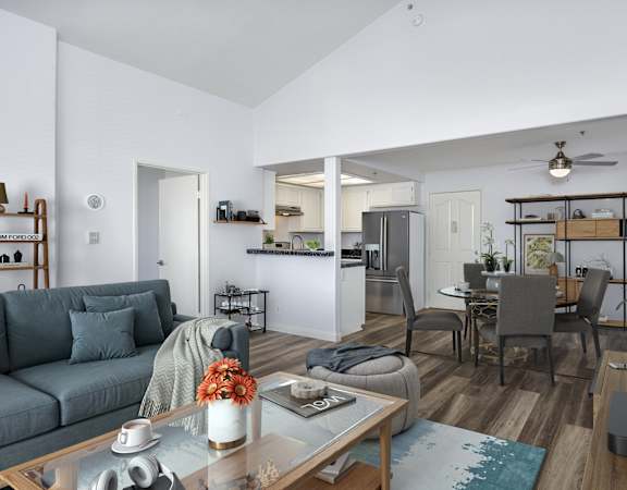 A modern living room with a grey sofa, a glass coffee table, and a television.