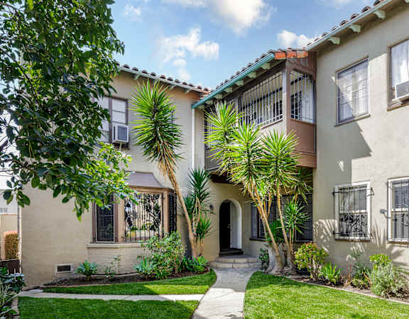 a house with a yard and palm trees in front of it