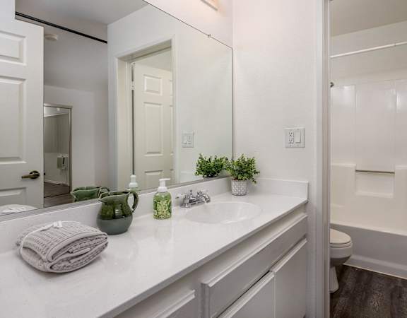 A white bathroom with a mirror, sink, and toilet.