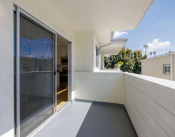 a balcony with a glass door and a white wall