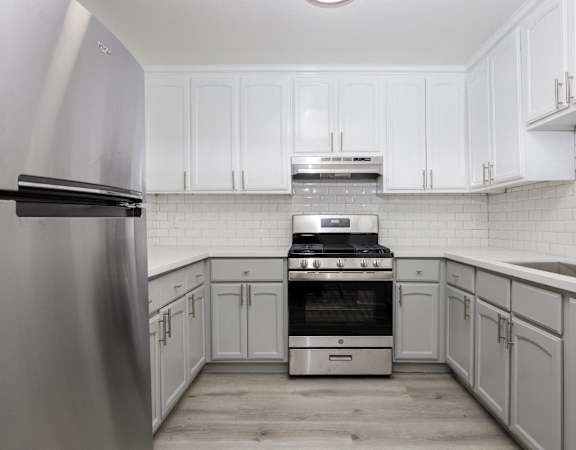 a white kitchen with white cabinets and stainless steel appliances