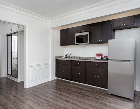 a kitchen with dark cabinets and a stainless steel refrigerator